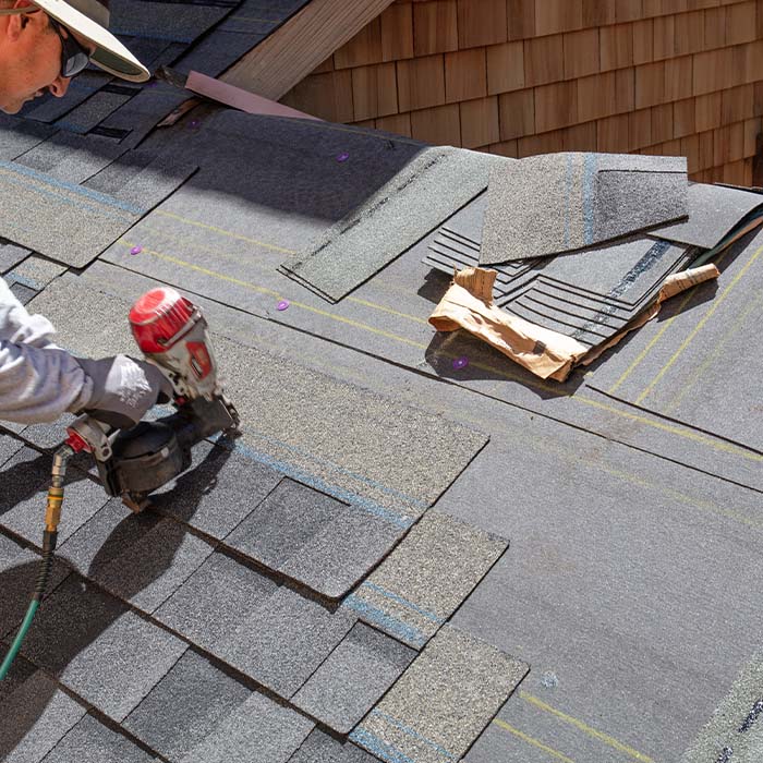 Installing new roof with nail gun and shingles